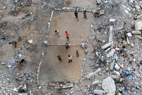 أطفال فلسطينيون يلعبون الكرة الطائرة على ملعب أُقيم بين أنقاض المباني التي دمرتها الحرب في مدينة غزة في 16 سبتمبر/أيلول 2026. صورة: بلال أسامة