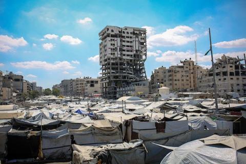 يعيش فلسطينيون نازحون في خيام قرب برج بنك فلسطين المتضرر، والذي يقول السكان إنه مُعرّض للانهيار، في مدينة غزة بتاريخ 20 سبتمبر/أيلول 2026. صورة: محمد صالحة