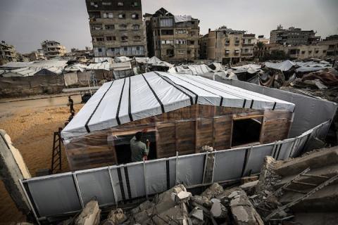 الفلسطيني هشام حميد يبني مأوى لعائلته من أخشاب المساعدات والطين قرب أنقاض منزله غرب مدينة غزة، استعدادًا لبرد الشتاء، 28 أكتوبر/تشرين الأول 2026. (تصوير: محمد صالحة)
