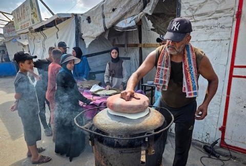 الفلسطيني مازن الدوش يُعدّ الخبز على صاج بدائي بين أنقاض المباني المدمرة في خان يونس، جنوب قطاع غزة، 9 تشرين الأول/أكتوبر 2026. (تصوير: طارق محمد)