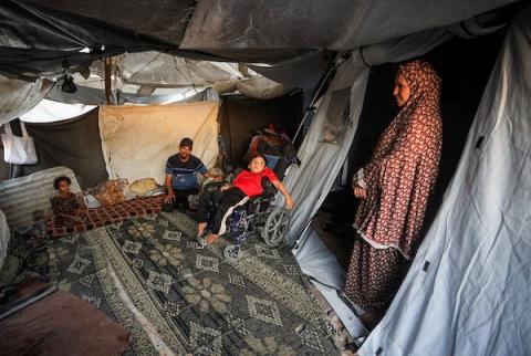 الطفلان الفلسطينيان إياد وميرا غبن، المصابان بالشلل الدماغي منذ الولادة، إلى جانب والديهما داخل خيمة نزوح غرب مدينة غزة، وسط نقص الرعاية الطبية والعلاج المتخصص، 29 أكتوبر 2026. (تصوير: محمد صالحة)