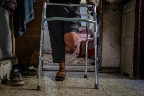 محمود فؤاد الدهشان (64 عامًا) يستعين بجهاز طبي للمشي في حي الزيتون بمدينة غزة، بعد فقدان قدمه اليسرى في قصف إسرائيلي عام 2023. (تصوير: بلال أسامة)