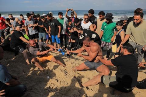 شبان فلسطينيون يمارسون تمارين وأنشطة رياضية على شاطئ النصيرات وسط قطاع غزة، يوم 16 أكتوبر/تشرين الأول 2026، في ظل تضرر المنشآت الرياضية وتعطّل أنشطة الأندية جراء الحرب، بحثاً عن متنفس للحفاظ على لياقتهم البدنية والتخفيف من التوتر. (تصوير: حسن الجدي)