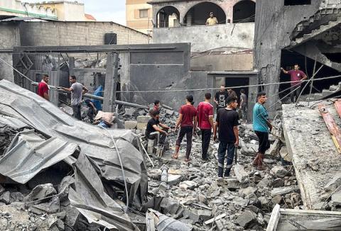 فلسطينيون يتفقدون ممتلكاتهم بين أنقاض المباني السكنية والخيام المتضررة جراء غارة جوية إسرائيلية استهدفت منزلًا في دير البلح وسط قطاع غزة، 11 أكتوبر/تشرين الأول 2026. (تصوير: أحمد إبراهيم)