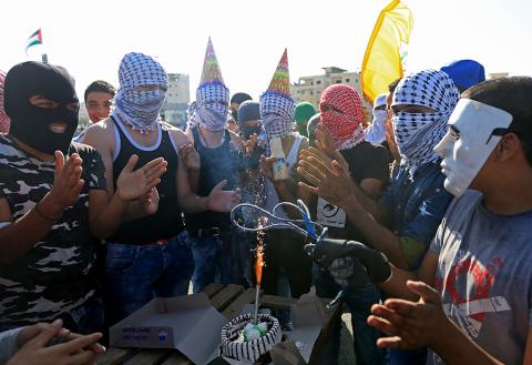 فتية فلسطينيون يحتفلون بيوم ميلاد أحد أصدقائهم خلال مواجهات مع قوات الاحتلال الاسرائيلي على المدخل الشمالي لمدينة البيرة. عدسة/ حذيفة سرور - وفا