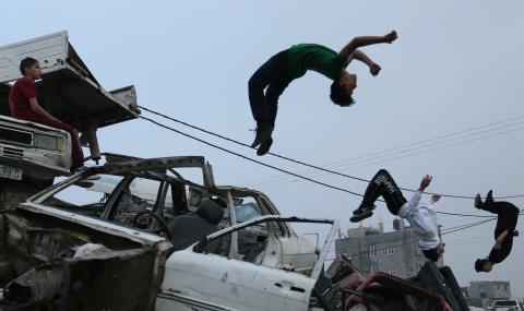 فتية فلسطينيون يمارسون رياضة "الباركور" في مكان لتجميع هياكل المركبات القديمة بقطاع غزة  المحاصر من قبل اسرائيل منذ 10 سنوات/عدسة: محمود عيسى