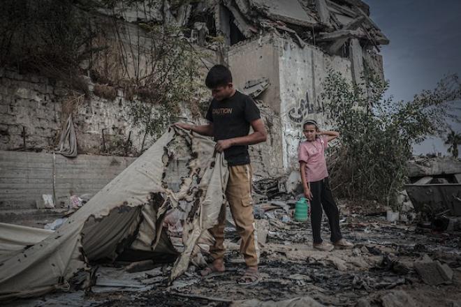 نازحون فلسطينيون يتفقدون بقايا خيامهم وممتلكاتهم التي أتت عليها النيران إثر غارة إسرائيلية قرب مفترق الشجاعية شرقي مدينة غزة، 26 أكتوبر 2026. (تصوير: بلال أسامة)