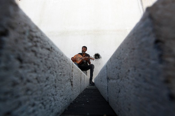 اللاجئ الفلسطيني كمال أبو غبن يعزف على آلة العود أثناء راحته في العمل20