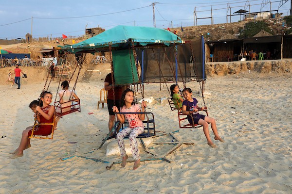فلسطينيون يستمتعون بأوقاتهم على شاطئ البحر في مدينة دير البلح وسط قطاع غزة. 24