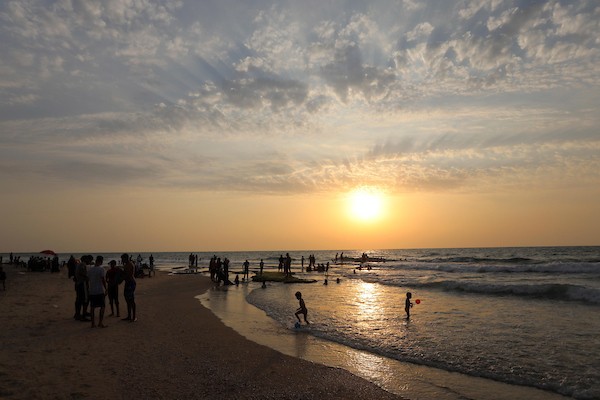 10فلسطينيون يستمتعون بأوقاتهم على شاطئ البحر في مدينة دير البلح وسط قطاع غزة.