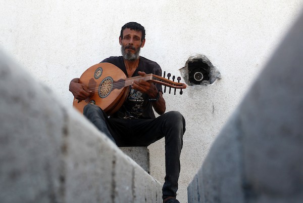 اللاجئ الفلسطيني كمال أبو غبن يعزف على آلة العود أثناء راحته في العمل19