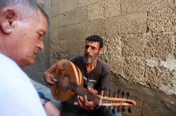 اللاجئ الفلسطيني كمال أبو غبن يعزف على آلة العود أثناء راحته في العمل3