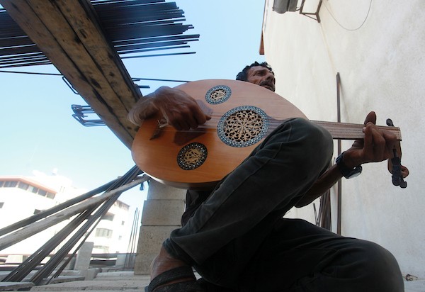 اللاجئ الفلسطيني كمال أبو غبن يعزف على آلة العود أثناء راحته في العمل 23