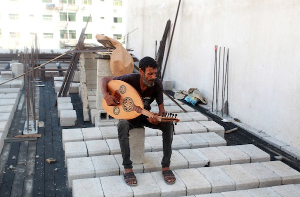 اللاجئ الفلسطيني كمال أبو غبن يعزف على آلة العود أثناء راحته في العمل21