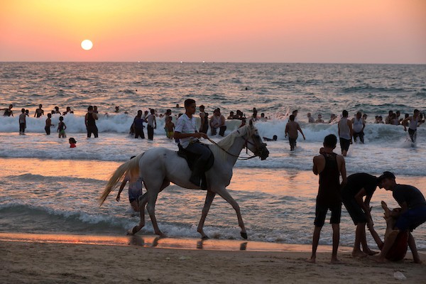 فلسطينيون يستمتعون بأوقاتهم على شاطئ البحر في مدينة دير البلح وسط قطاع غزة.4
