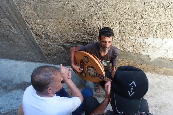 اللاجئ الفلسطيني كمال أبو غبن يعزف على آلة العود أثناء راحته في العمل 7