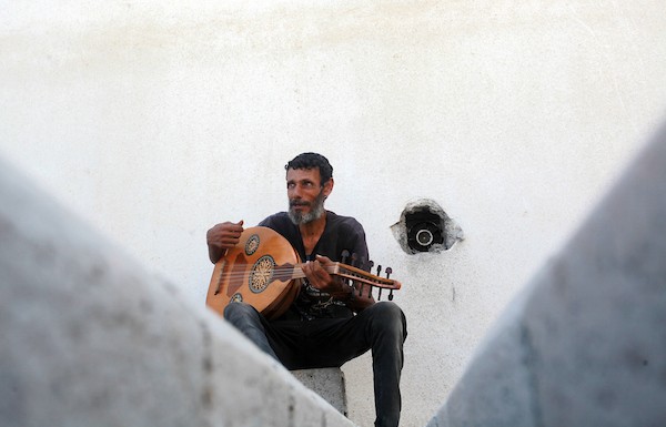 اللاجئ الفلسطيني كمال أبو غبن يعزف على آلة العود أثناء راحته في العمل 18