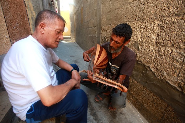 اللاجئ الفلسطيني كمال أبو غبن يعزف على آلة العود أثناء راحته في العمل 2
