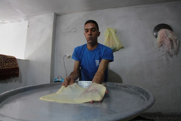 الشاب الفلسطيني أحمد علي ، 31 عامًا ، يصنع فطير مشلتت ، في متجره في مخيم الشاطئ ، في مدينة غزة  12.JPG