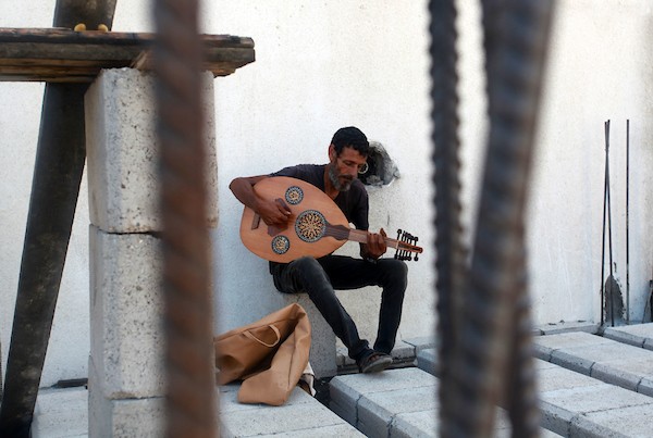 اللاجئ الفلسطيني كمال أبو غبن يعزف على آلة العود أثناء راحته في العمل 17