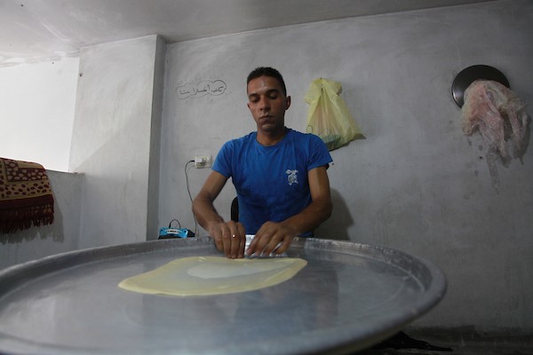 الشاب الفلسطيني أحمد علي ، 31 عامًا ، يصنع فطير مشلتت ، في متجره في مخيم الشاطئ ، في مدينة غزة  32.JPG