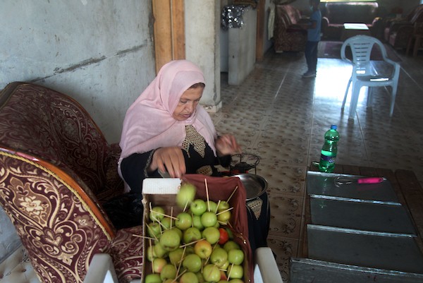 الفلسطينية حنان حمد ، 50 عاما ، تصنع حلوى التفاح بالعسل الملون المعروف في غزة باسم 