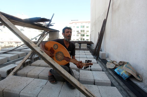 اللاجئ الفلسطيني كمال أبو غبن يعزف على آلة العود أثناء راحته في العمل22