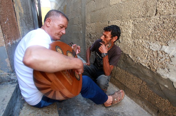 اللاجئ الفلسطيني كمال أبو غبن يعزف على آلة العود أثناء راحته في العمل 1