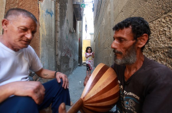 اللاجئ الفلسطيني كمال أبو غبن يعزف على آلة العود أثناء راحته في العمل 6
