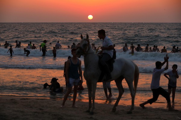 فلسطينيون يستمتعون بأوقاتهم على شاطئ البحر في مدينة دير البلح وسط قطاع غزة.26