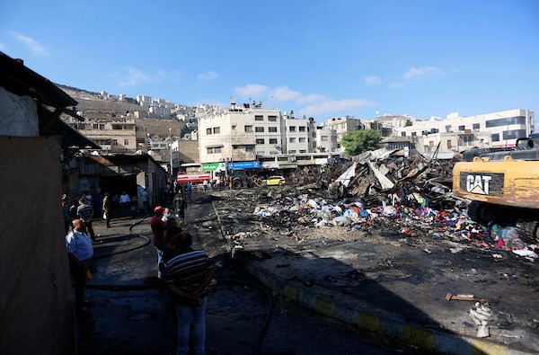فلسطينيون يتفقدون آثار الحريق الذي التهم محالهم وبسطاتهم في سوق لبيع البضائع المستعملة في المنطقة الشرقية في مدينة نابلس 11