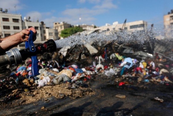 فلسطينيون يتفقدون آثار الحريق الذي التهم محالهم وبسطاتهم في سوق لبيع البضائع المستعملة في المنطقة الشرقية في مدينة نابلس