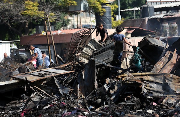 فلسطينيون يتفقدون آثار الحريق الذي التهم محالهم وبسطاتهم في سوق لبيع البضائع المستعملة في المنطقة الشرقية في مدينة نابلس 13