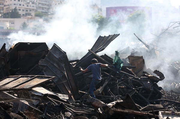 فلسطينيون يتفقدون آثار الحريق الذي التهم محالهم وبسطاتهم في سوق لبيع البضائع المستعملة في المنطقة الشرقية في مدينة نابلس 2