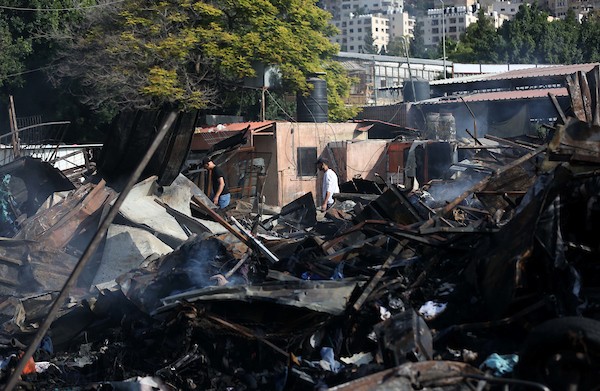 فلسطينيون يتفقدون آثار الحريق الذي التهم محالهم وبسطاتهم في سوق لبيع البضائع المستعملة في المنطقة الشرقية في مدينة نابلس 10