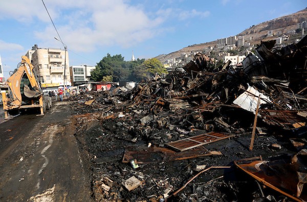 فلسطينيون يتفقدون آثار الحريق الذي التهم محالهم وبسطاتهم في سوق لبيع البضائع المستعملة في المنطقة الشرقية في مدينة نابلس