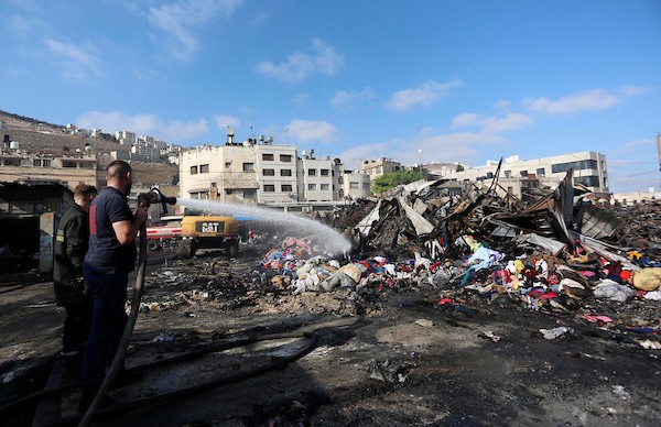 فلسطينيون يتفقدون آثار الحريق الذي التهم محالهم وبسطاتهم في سوق لبيع البضائع المستعملة في المنطقة الشرقية في مدينة نابلس 14