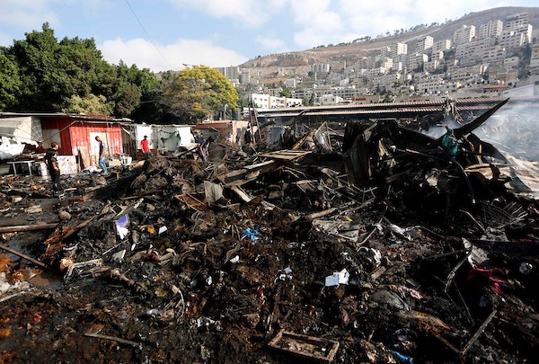 فلسطينيون يتفقدون آثار الحريق الذي التهم محالهم وبسطاتهم في سوق لبيع البضائع المستعملة في المنطقة الشرقية في مدينة نابلس