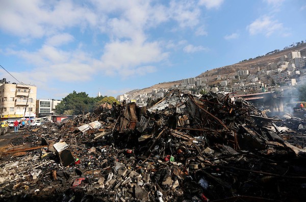 فلسطينيون يتفقدون آثار الحريق الذي التهم محالهم وبسطاتهم في سوق لبيع البضائع المستعملة في المنطقة الشرقية في مدينة نابلس 3