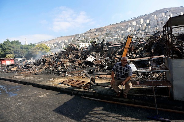فلسطينيون يتفقدون آثار الحريق الذي التهم محالهم وبسطاتهم في سوق لبيع البضائع المستعملة في المنطقة الشرقية في مدينة نابلس 15