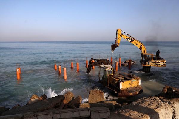 عمال فلسطينيون يديرون جرافة لنصب ركائز في البحر الأبيض المتوسط ​​لبناء مقهى القلعة وهو أول مقهى خرساني عائم على شاطئ مدينة غزة باستخدام مواد بسيطة 21