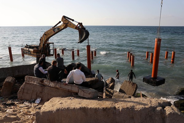 عمال فلسطينيون يديرون جرافة لنصب ركائز في البحر الأبيض المتوسط ​​لبناء مقهى القلعة وهو أول مقهى خرساني عائم على شاطئ مدينة غزة باستخدام مواد بسيطة 22