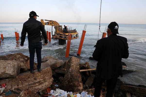عمال فلسطينيون يديرون جرافة لنصب ركائز في البحر الأبيض المتوسط ​​لبناء مقهى القلعة وهو أول مقهى خرساني عائم على شاطئ مدينة غزة باستخدام مواد بسيطة 15