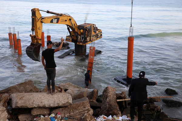 عمال فلسطينيون يديرون جرافة لنصب ركائز في البحر الأبيض المتوسط ​​لبناء مقهى القلعة وهو أول مقهى خرساني عائم على شاطئ مدينة غزة باستخدام مواد بسيطة 13