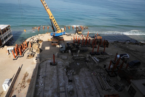 عمال فلسطينيون يديرون جرافة لنصب ركائز في البحر الأبيض المتوسط ​​لبناء مقهى القلعة وهو أول مقهى خرساني عائم على شاطئ مدينة غزة باستخدام مواد بسيطة 25