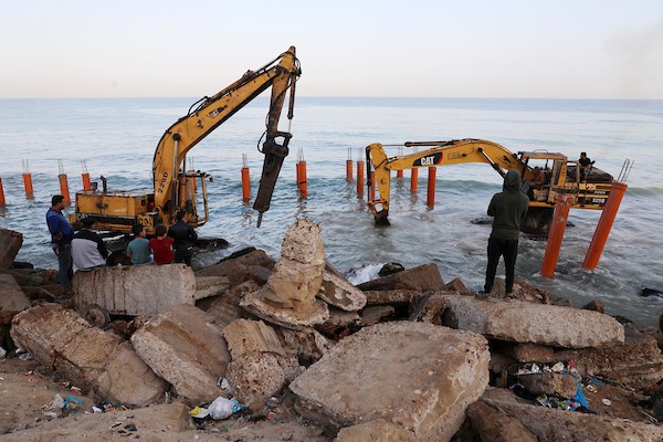 عمال فلسطينيون يديرون جرافة لنصب ركائز في البحر الأبيض المتوسط ​​لبناء مقهى القلعة وهو أول مقهى خرساني عائم على شاطئ مدينة غزة باستخدام مواد بسيطة 16