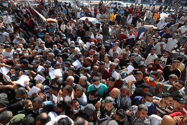 مواطنون فلسطينيون ينتظرون أمام مقر الغرفة التجارية للتسجيل من اجل العمل في إسرائيل، في دير البلح وسط قطاع غزة(24)