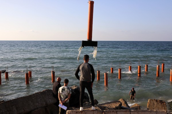 عمال فلسطينيون يديرون جرافة لنصب ركائز في البحر الأبيض المتوسط ​​لبناء مقهى القلعة وهو أول مقهى خرساني عائم على شاطئ مدينة غزة باستخدام مواد بسيطة 18