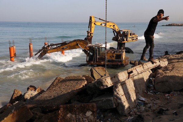 عمال فلسطينيون يديرون جرافة لنصب ركائز في البحر الأبيض المتوسط ​​لبناء مقهى القلعة وهو أول مقهى خرساني عائم على شاطئ مدينة غزة باستخدام مواد بسيطة 32