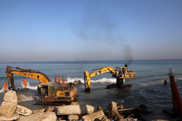عمال فلسطينيون يديرون جرافة لنصب ركائز في البحر الأبيض المتوسط ​​لبناء مقهى القلعة وهو أول مقهى خرساني عائم على شاطئ مدينة غزة باستخدام مواد بسيطة 9